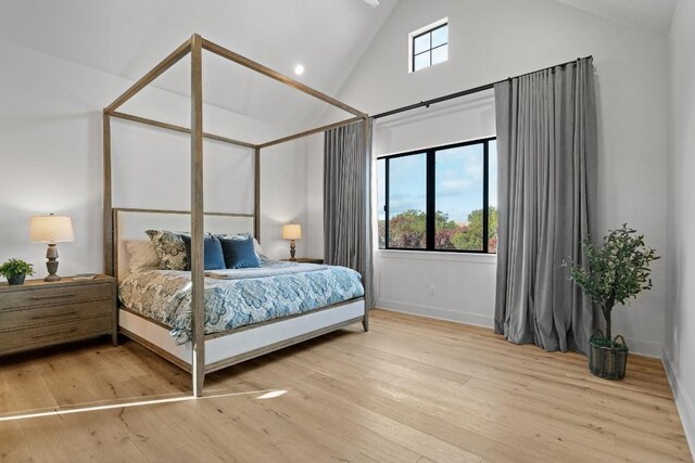 bedroom with high vaulted ceiling and wood-type flooring