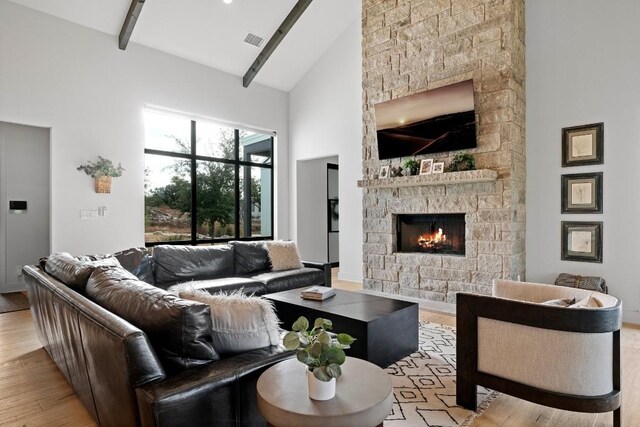 living room with light wood-type flooring, high vaulted ceiling, a fireplace, and beamed ceiling