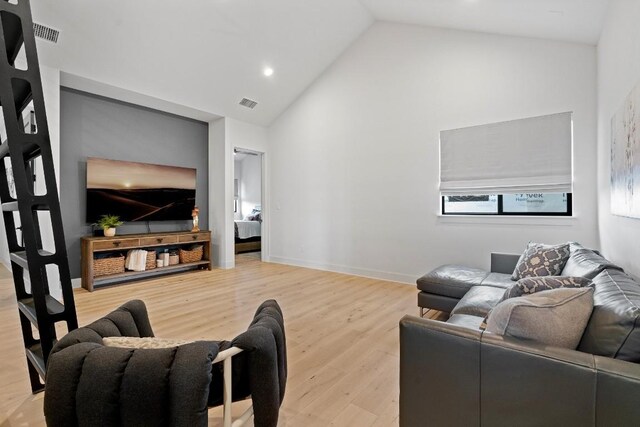 living room with light wood-type flooring and vaulted ceiling