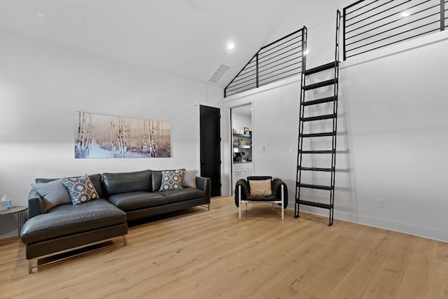 living room with high vaulted ceiling and light wood-type flooring