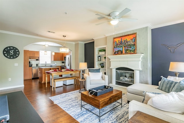 living room with dark hardwood / wood-style flooring, ceiling fan, crown molding, and sink