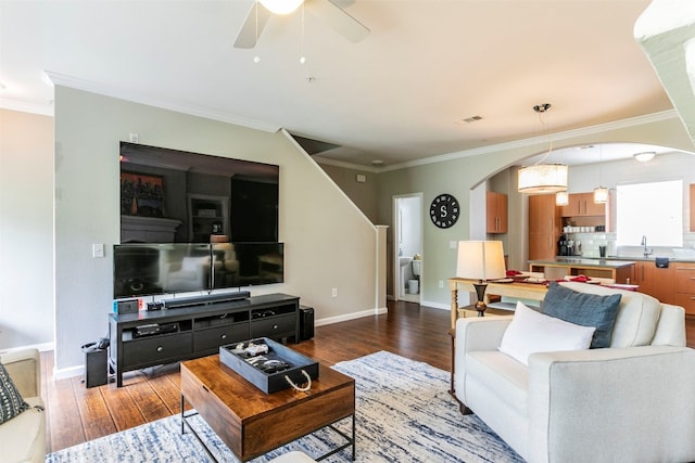 living room with crown molding, dark wood-type flooring, ceiling fan, and sink