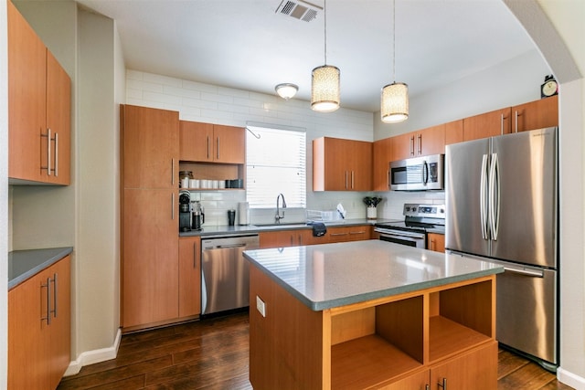 kitchen with a center island, sink, hanging light fixtures, dark hardwood / wood-style flooring, and stainless steel appliances