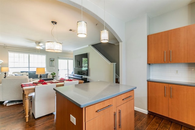 kitchen with hanging light fixtures, a kitchen island, ceiling fan, dark hardwood / wood-style floors, and tasteful backsplash