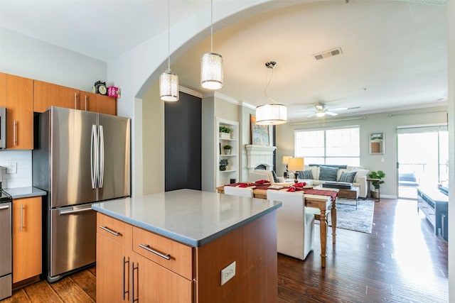 kitchen with a center island, pendant lighting, dark hardwood / wood-style flooring, and stainless steel fridge