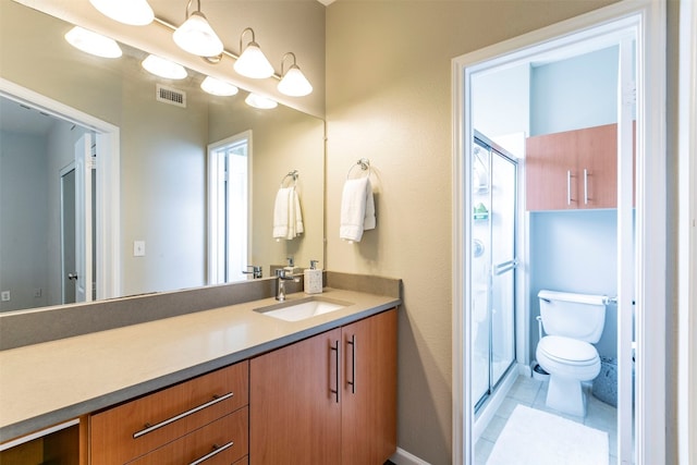 bathroom featuring vanity with extensive cabinet space, toilet, tile flooring, and walk in shower