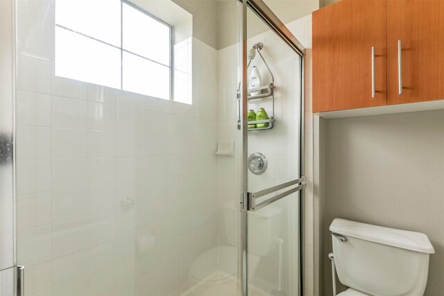 bathroom featuring walk in shower and toilet