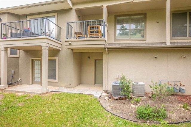 rear view of property with a yard, a balcony, and central air condition unit