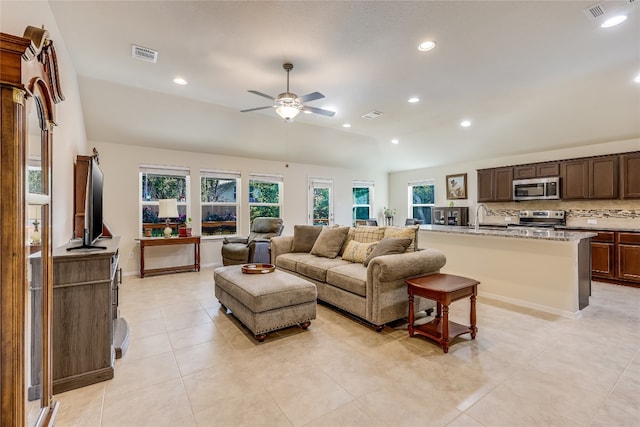 living room with ceiling fan, sink, light tile patterned flooring, and lofted ceiling