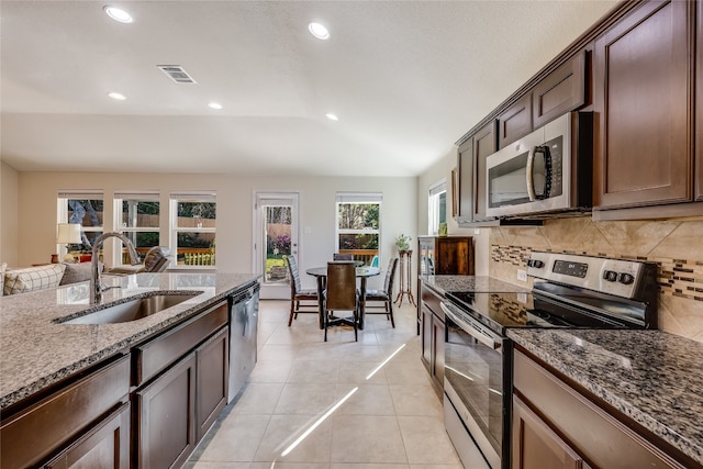 kitchen featuring sink, tasteful backsplash, stone countertops, light tile patterned floors, and appliances with stainless steel finishes