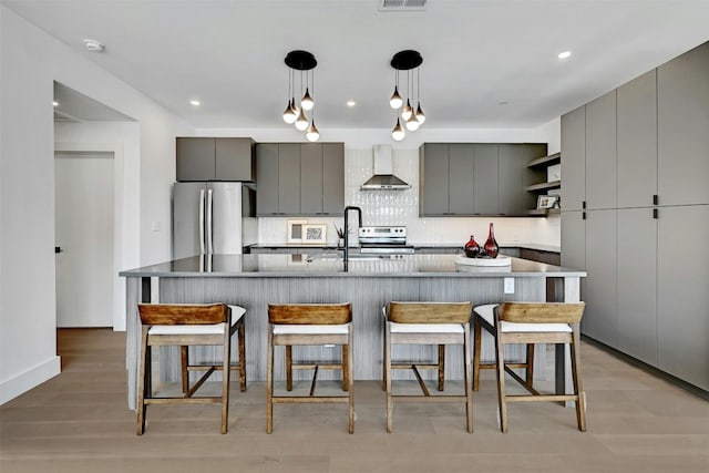 kitchen featuring appliances with stainless steel finishes, gray cabinetry, and wall chimney exhaust hood