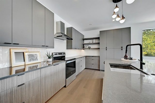 kitchen with stainless steel range with electric stovetop, wall chimney range hood, pendant lighting, and gray cabinetry