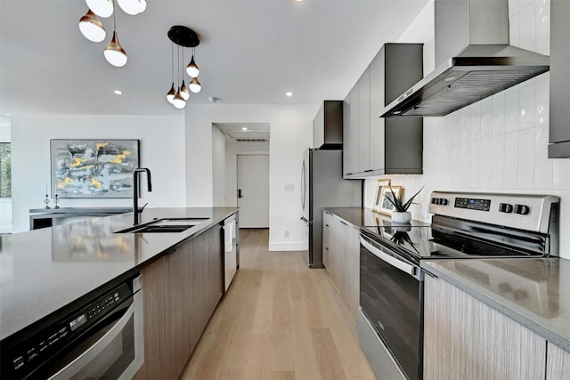 kitchen with extractor fan, appliances with stainless steel finishes, decorative light fixtures, sink, and light wood-type flooring