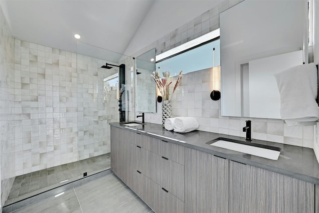 bathroom featuring vaulted ceiling, a tile shower, backsplash, tile patterned flooring, and vanity