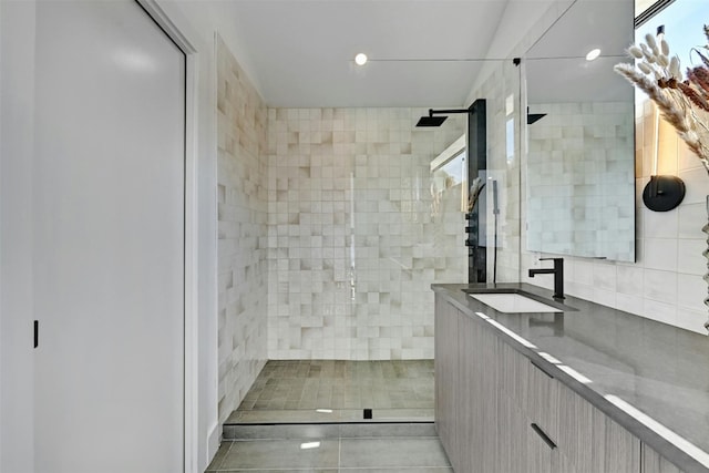 bathroom featuring tile walls, vanity, tile patterned flooring, and a tile shower