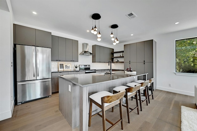 kitchen with wall chimney exhaust hood, a kitchen bar, sink, decorative light fixtures, and stainless steel appliances