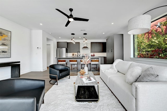 living room with sink, light hardwood / wood-style floors, and ceiling fan