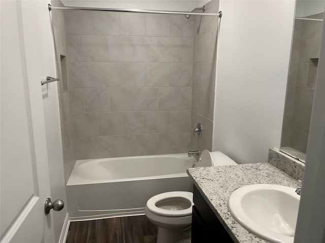 full bathroom featuring wood-type flooring, tiled shower / bath, toilet, and large vanity