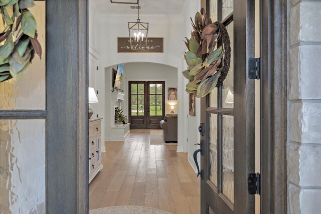 foyer with french doors, light hardwood / wood-style flooring, and crown molding