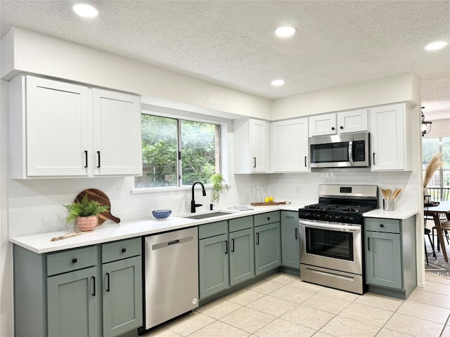 kitchen featuring backsplash, white cabinets, sink, a textured ceiling, and stainless steel appliances