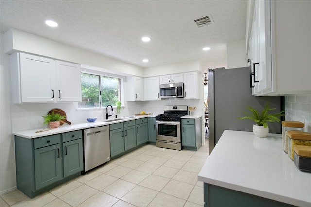 kitchen with appliances with stainless steel finishes, tasteful backsplash, sink, green cabinetry, and white cabinets