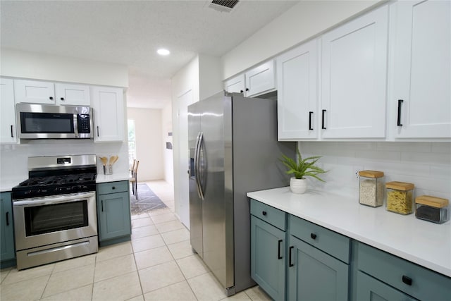 kitchen with backsplash, white cabinets, light tile patterned floors, and appliances with stainless steel finishes