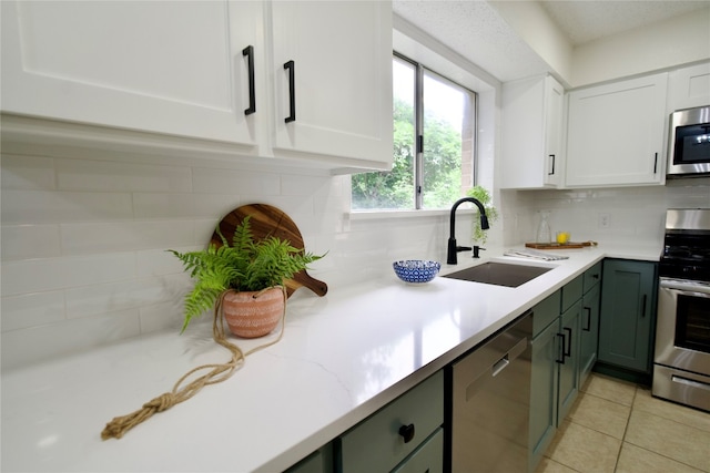 kitchen with backsplash, white cabinets, sink, green cabinetry, and stainless steel appliances