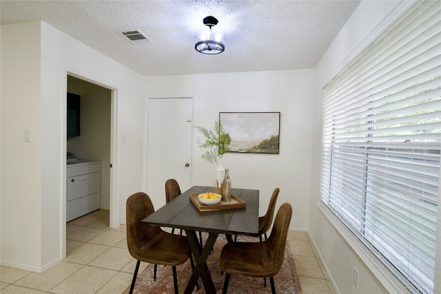 dining space featuring light tile patterned floors, a textured ceiling, and washer / clothes dryer