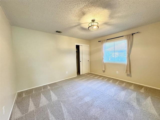 empty room with carpet floors and a textured ceiling