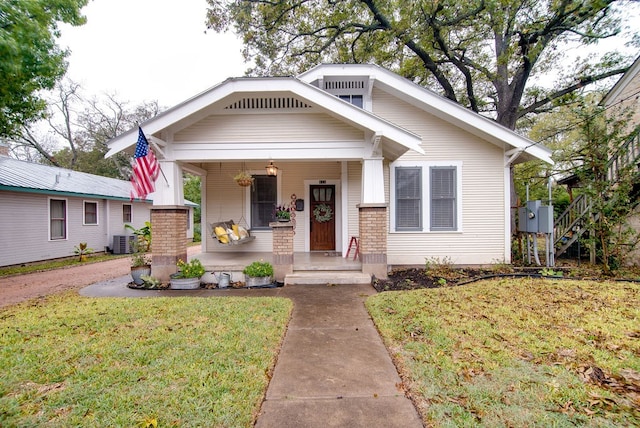 bungalow featuring central AC unit, covered porch, and a front yard