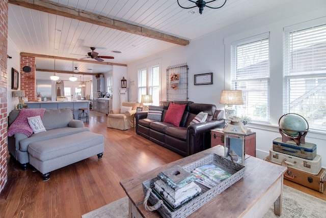 living room featuring beamed ceiling, ceiling fan, hardwood / wood-style flooring, and plenty of natural light