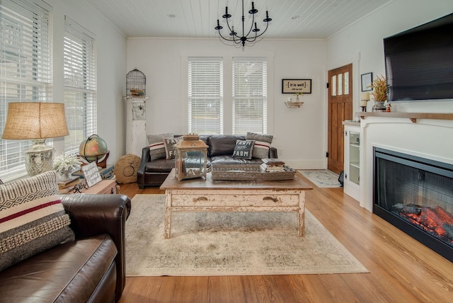 living room with ornamental molding, plenty of natural light, an inviting chandelier, and light hardwood / wood-style floors