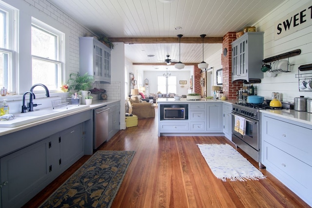 kitchen with appliances with stainless steel finishes, dark hardwood / wood-style floors, beamed ceiling, and hanging light fixtures