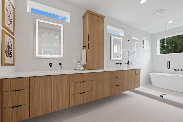 bathroom with tile patterned flooring, vanity, backsplash, tile walls, and a bathtub