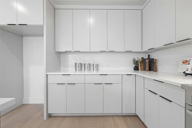 kitchen with white cabinets, light wood-type flooring, and tasteful backsplash