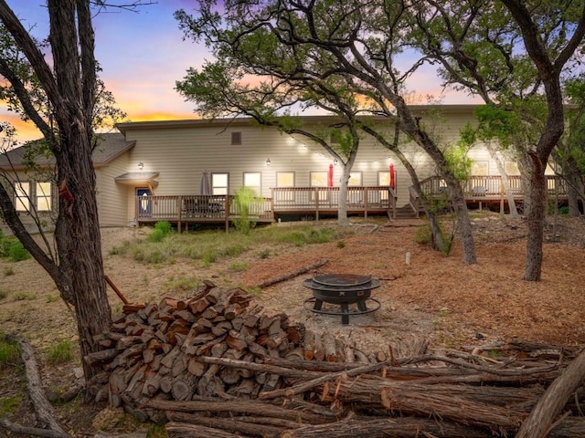 back house at dusk with a deck and a fire pit