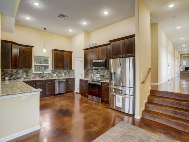 kitchen featuring dark brown cabinetry, backsplash, stainless steel appliances, pendant lighting, and light stone countertops