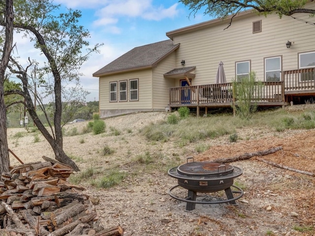 rear view of property featuring an outdoor fire pit and a wooden deck