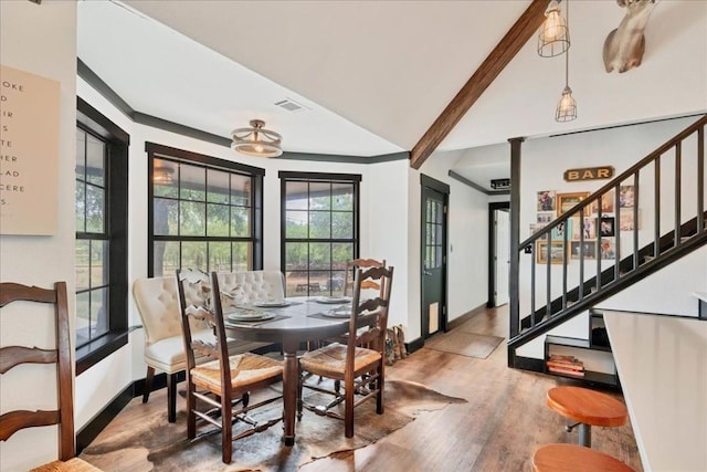 dining room with vaulted ceiling with beams and hardwood / wood-style flooring