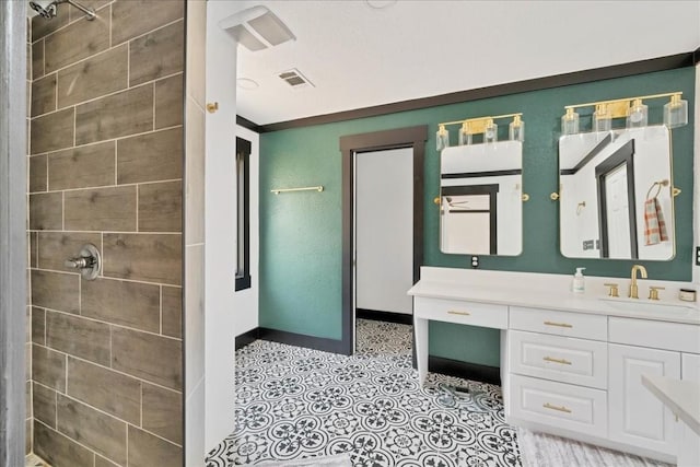 bathroom featuring a tile shower, vanity, and ornamental molding