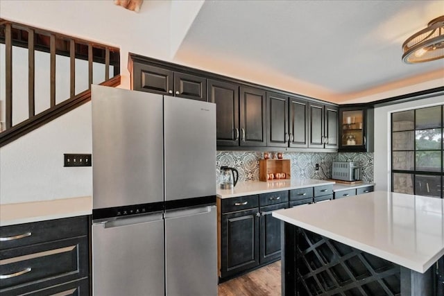 kitchen with decorative backsplash, stainless steel fridge, a center island, and light hardwood / wood-style floors