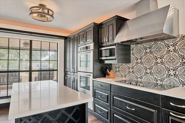 kitchen featuring backsplash, appliances with stainless steel finishes, wall chimney exhaust hood, and a kitchen island