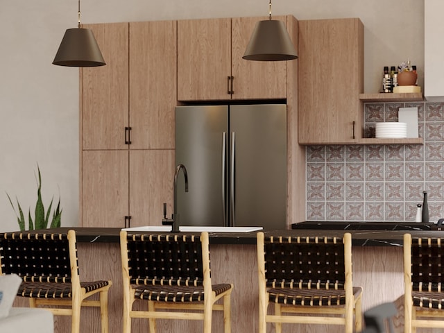 kitchen with hanging light fixtures, a breakfast bar, stainless steel refrigerator, and light brown cabinets