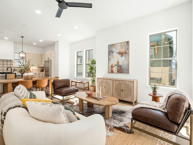 living room with sink, ceiling fan, and light wood-type flooring