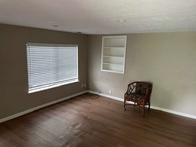 unfurnished room with dark hardwood / wood-style floors and built in shelves