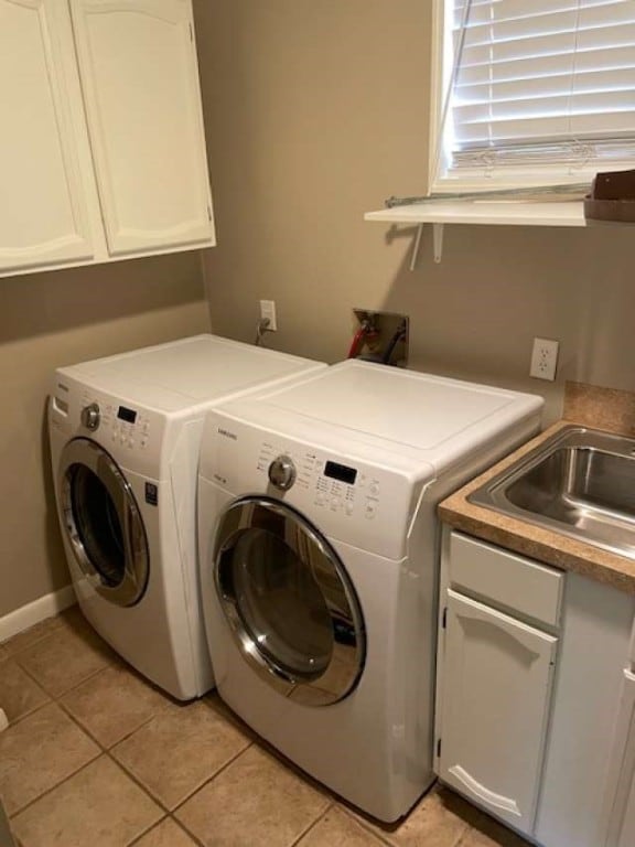 laundry area with cabinets, sink, light tile flooring, and washer and clothes dryer