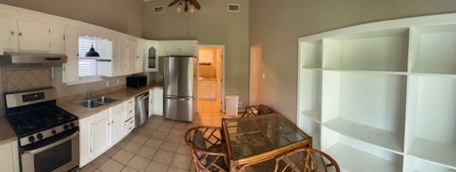 kitchen with stainless steel appliances, white cabinets, light tile floors, and exhaust hood