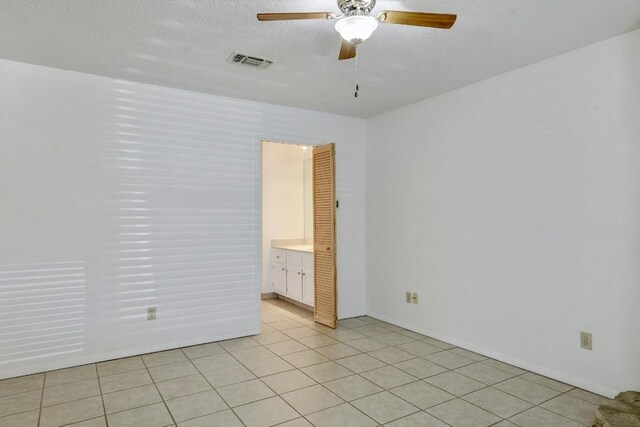 tiled spare room with a textured ceiling and ceiling fan