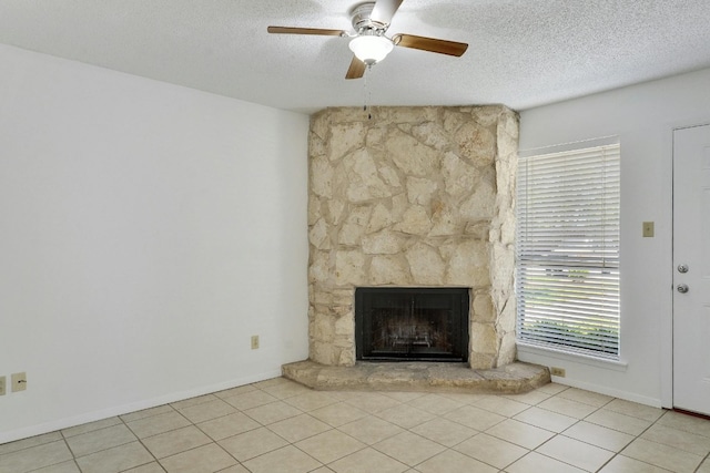 unfurnished living room with a textured ceiling, a fireplace, light tile flooring, and ceiling fan