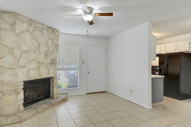 unfurnished living room featuring a textured ceiling, a fireplace, ceiling fan, and light tile floors